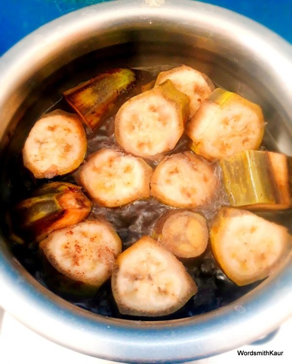 Add ginger and 1 black cardamom to the boiling bananas. Once the bananas are cooked but at bite like consistency, remove from fire. It will take 10 to 15 minutes in an open pan.