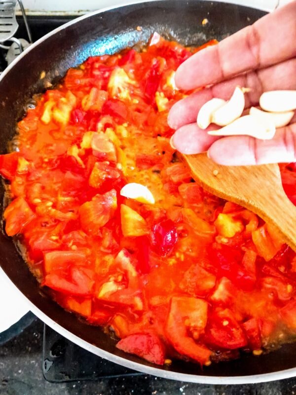 Next, heat the oil. Now, add the crushed garlic cloves and then the chopped tomatoes.